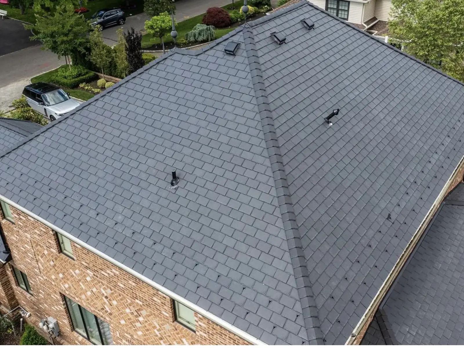 Aerial view of a finished grey architectural shingle roof over a brick home