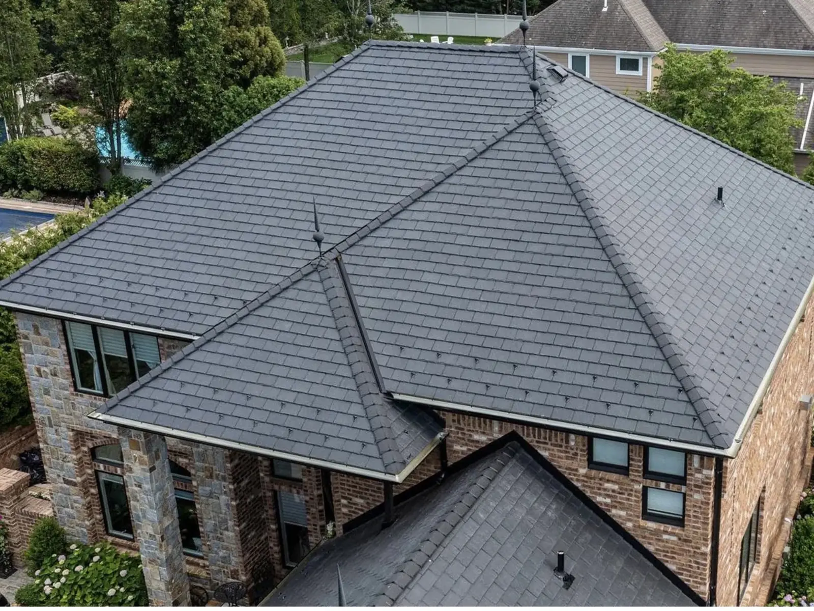 Aerial view of a finished shingle roof over a home with a backyard pool