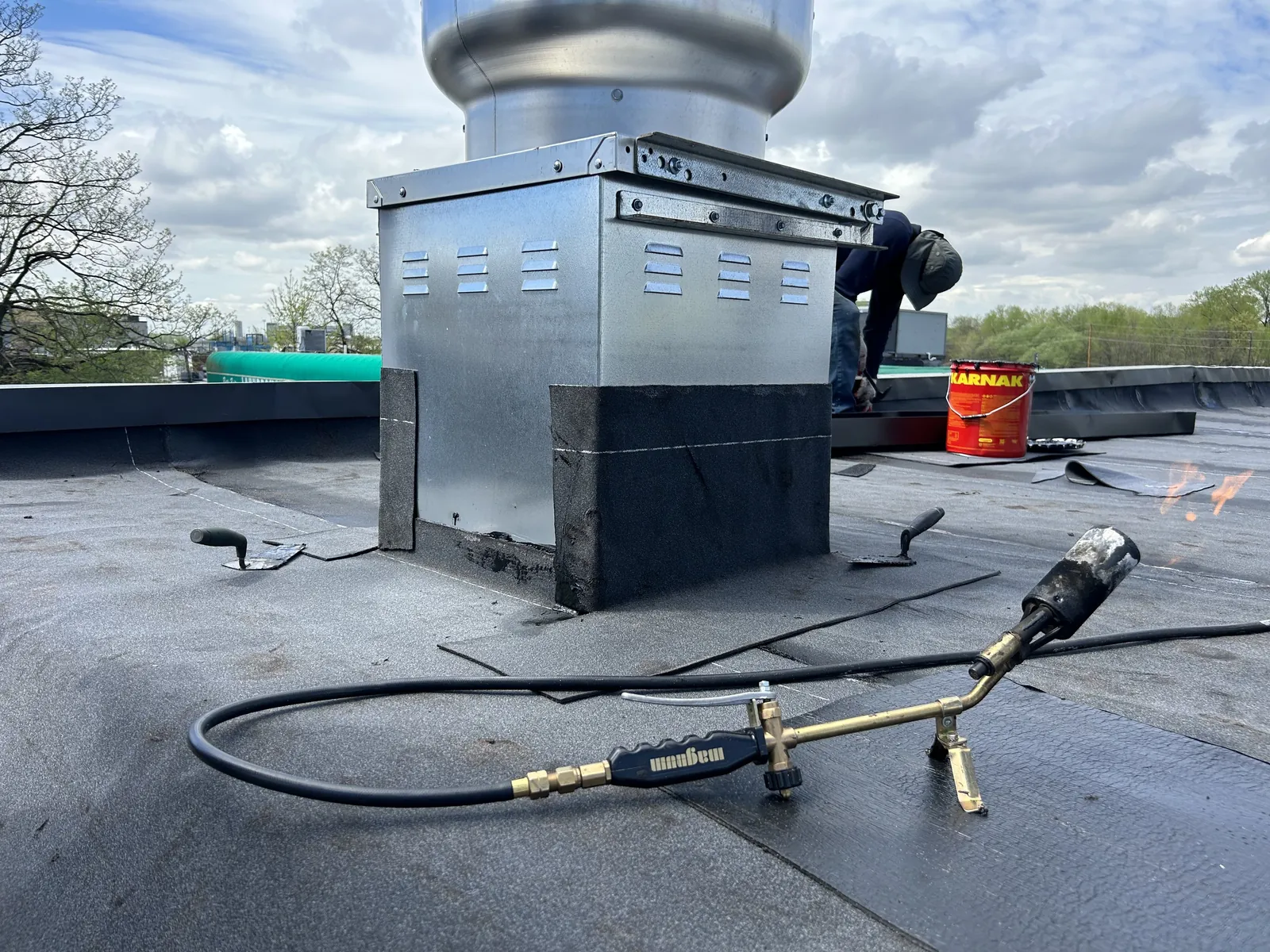 A Skyline Construction Group roofer torching down a flat roof detail