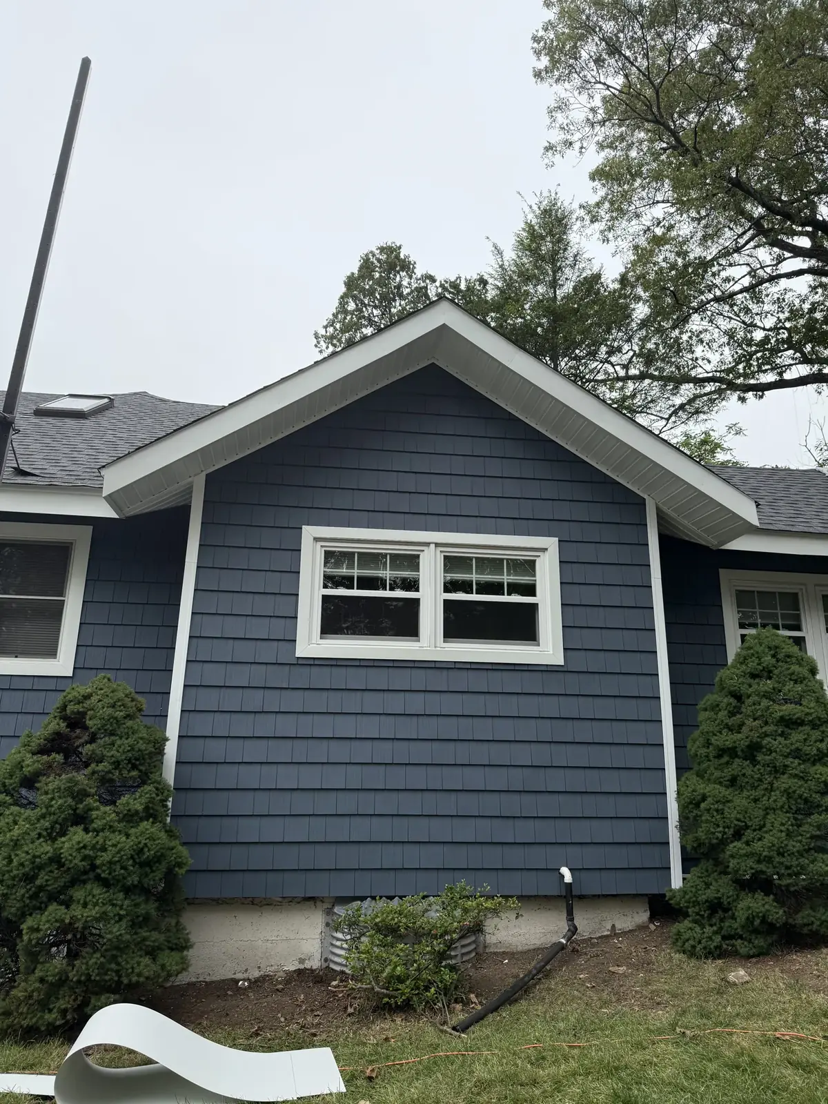 Close view of a finished blue shake siding gable with white window trim