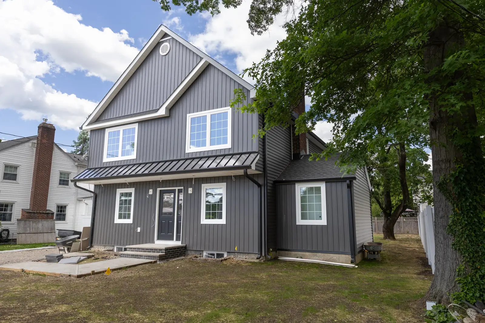 A finished dark board and batten siding home, rear elevation with a black door and white trim