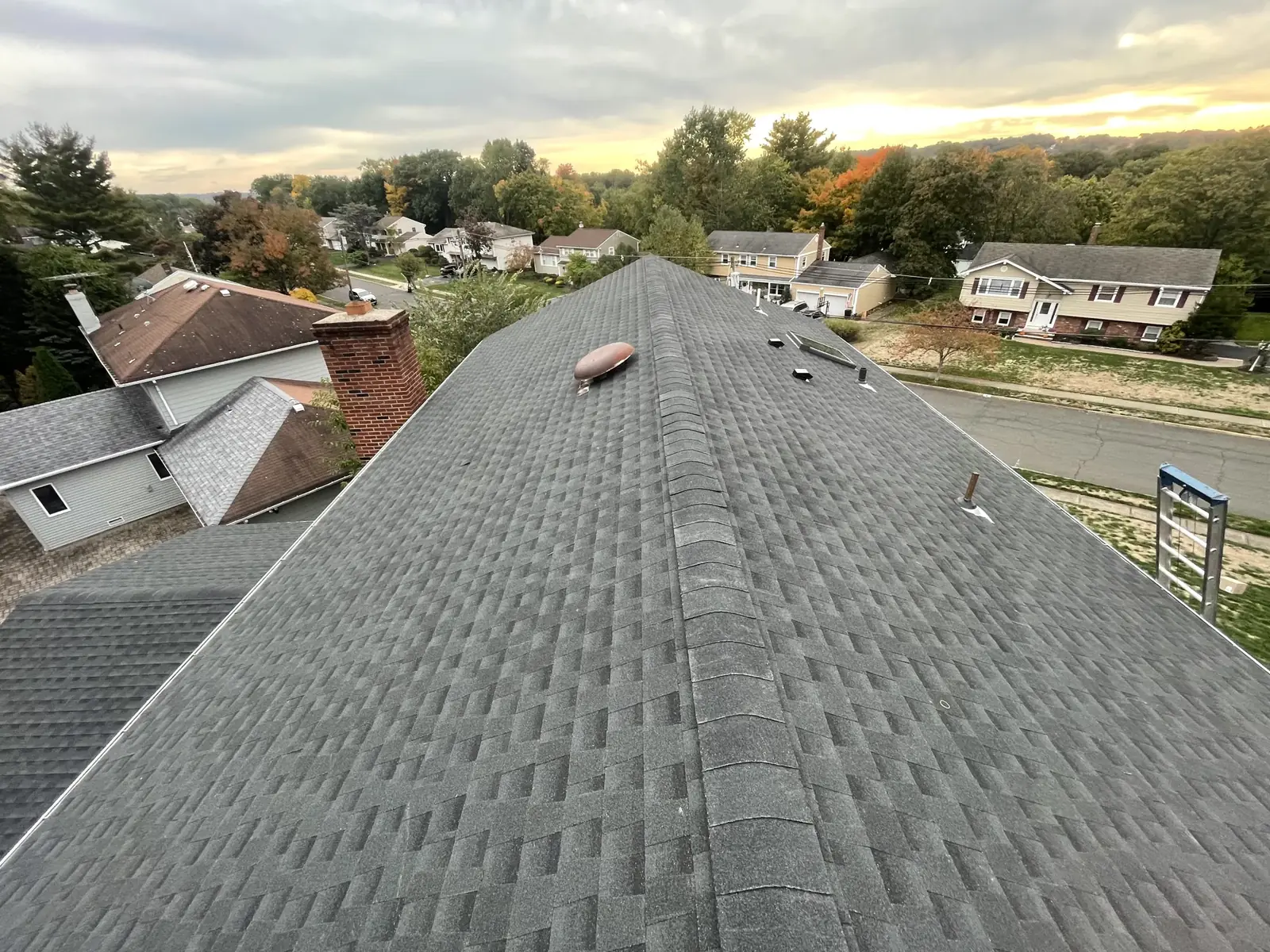 A finished shingle roof ridge at sunset