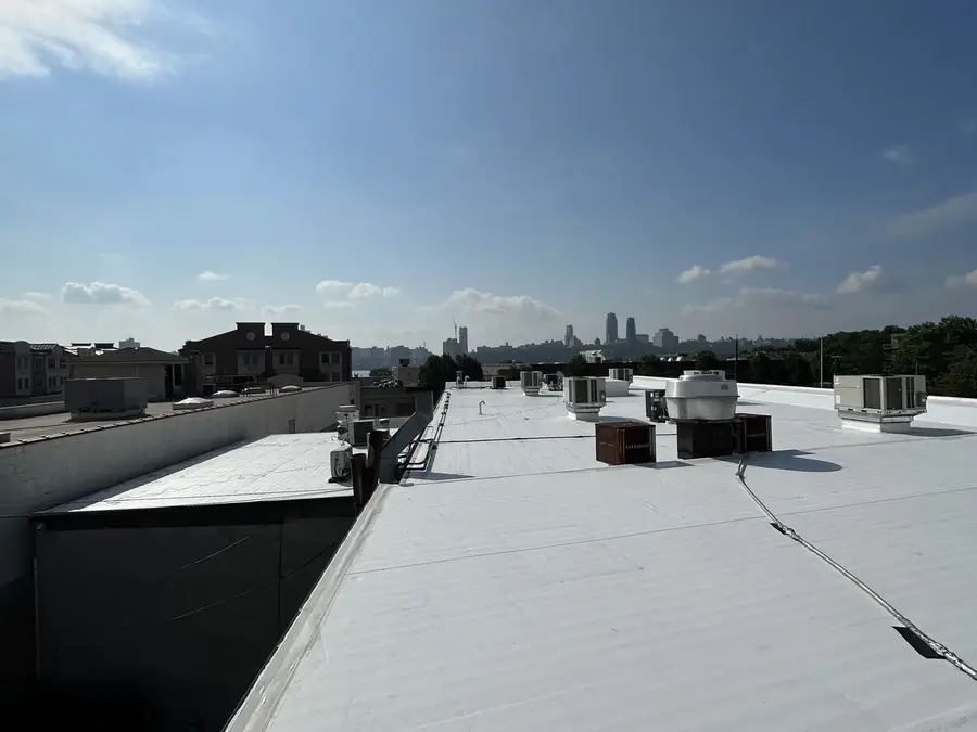 Large finished flat commercial roof with rooftop HVAC units and a city skyline view in the distance