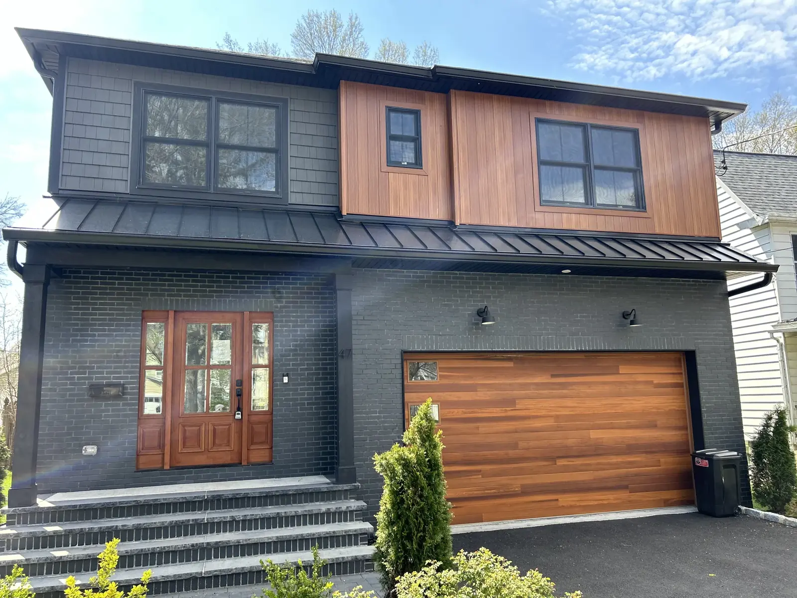 The same finished modern grey siding home straight on, showing the garage and the entry